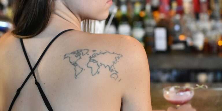 Femme avec un tatouage de carte du monde visible dans le dos
