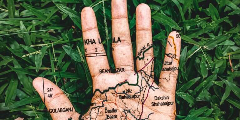 Paume de main tatouée d'une carte détaillée, sur fond d'herbe